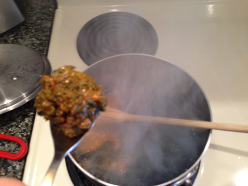 Spooning falafel into deep frying fluid made of tamarind and oil.